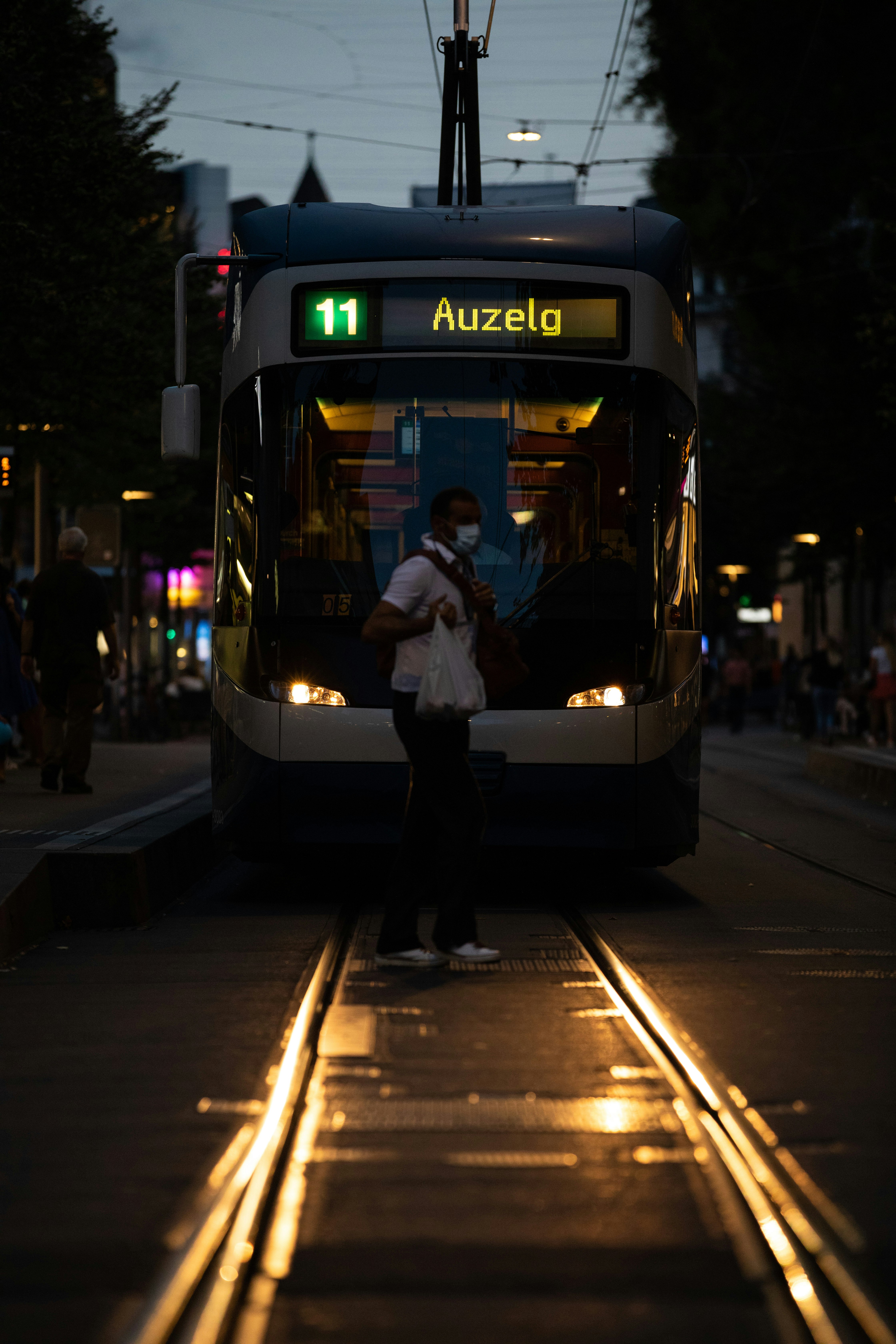 man in white dress shirt standing beside white and black train during night time